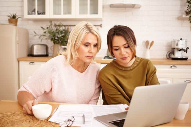 mom and teen daughter looking at colleges on computer