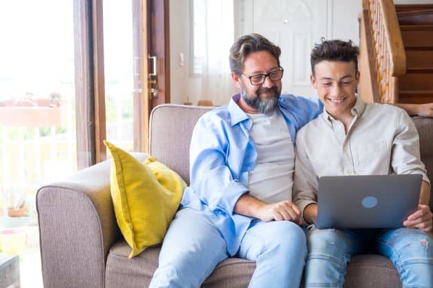 teen boy and dad looking at colleges on computer